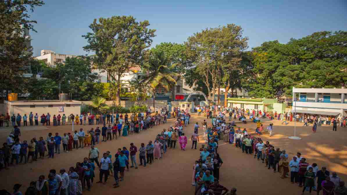मतदान केंद्र पर लंबी कतार में खड़े लोग, लोकतंत्र में भागीदारी दर्शाते हुए
