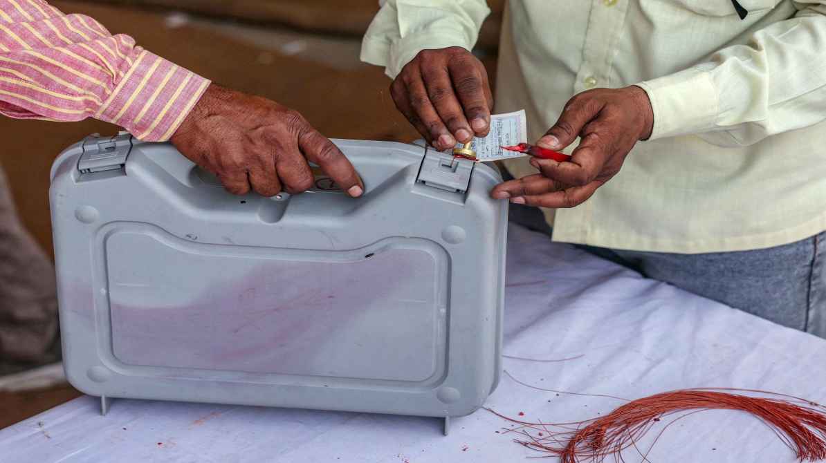 चुनाव के दौरान पोलिंग बूथ पर रखी EVM मशीन, जहां अधिकारी बटन की जांच कर रहे हैं